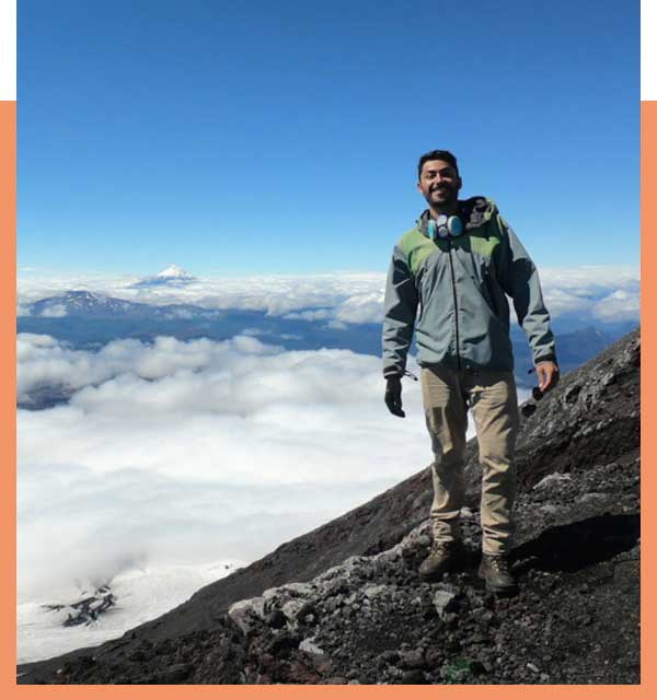 Climber standing on mountainside above the cloudline.