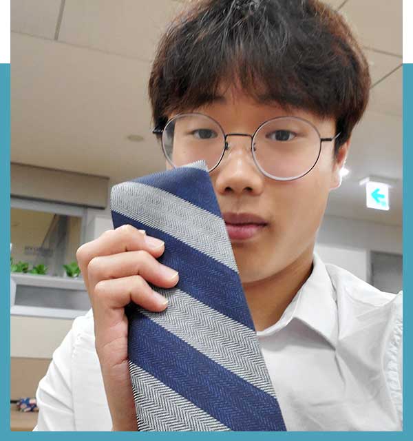 Studentwaering glasses holding up striped blue and gray tie.