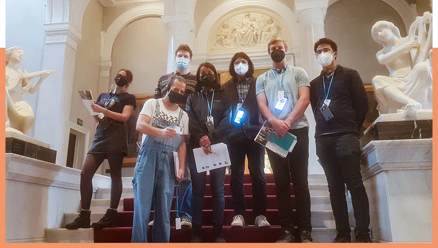 group of masked students on stairs with statues 