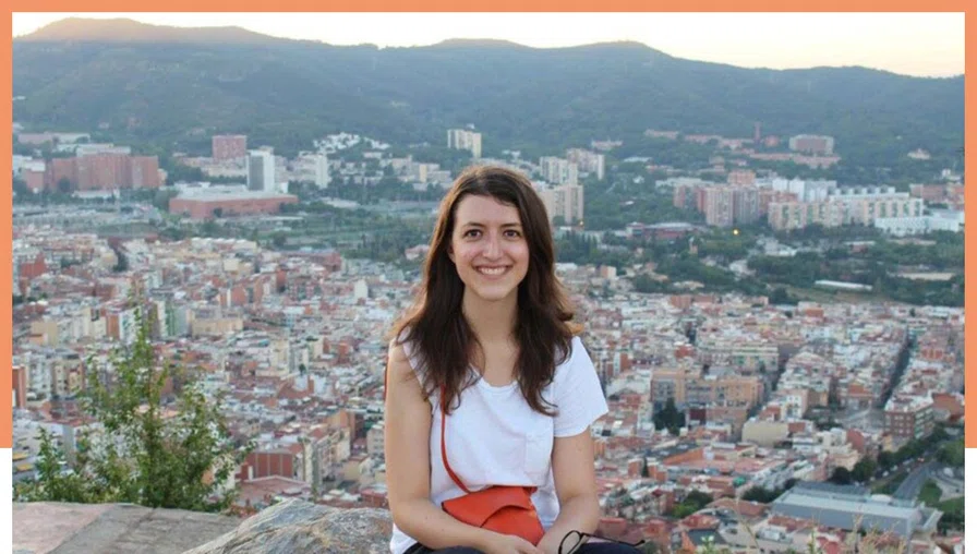 person smiling for camera with view of Barcelona cityscape behind.